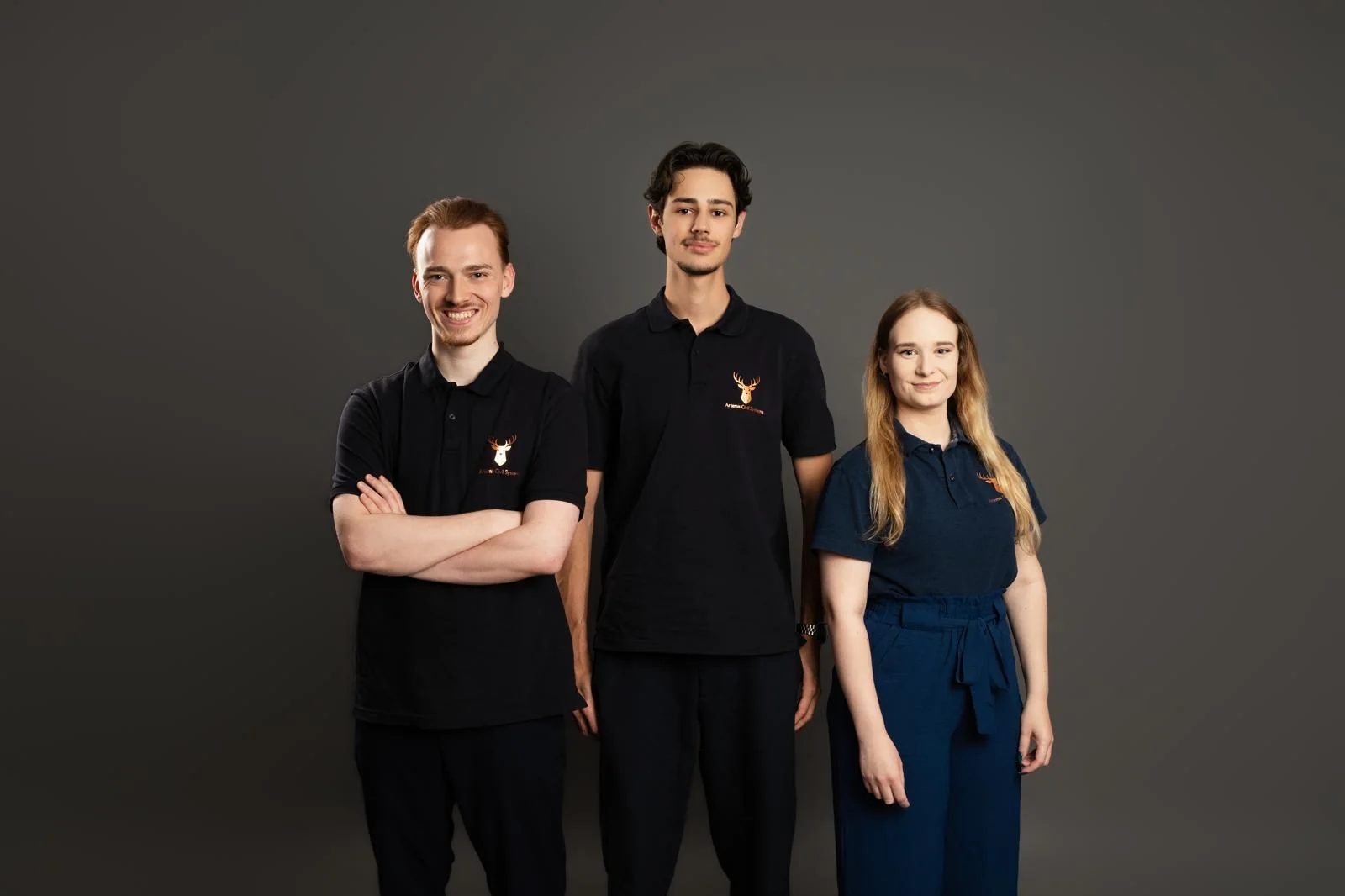 Simon, Marc und Selina im Studio, alle in dunklen Poloshirts mit dem Artemis-Logo